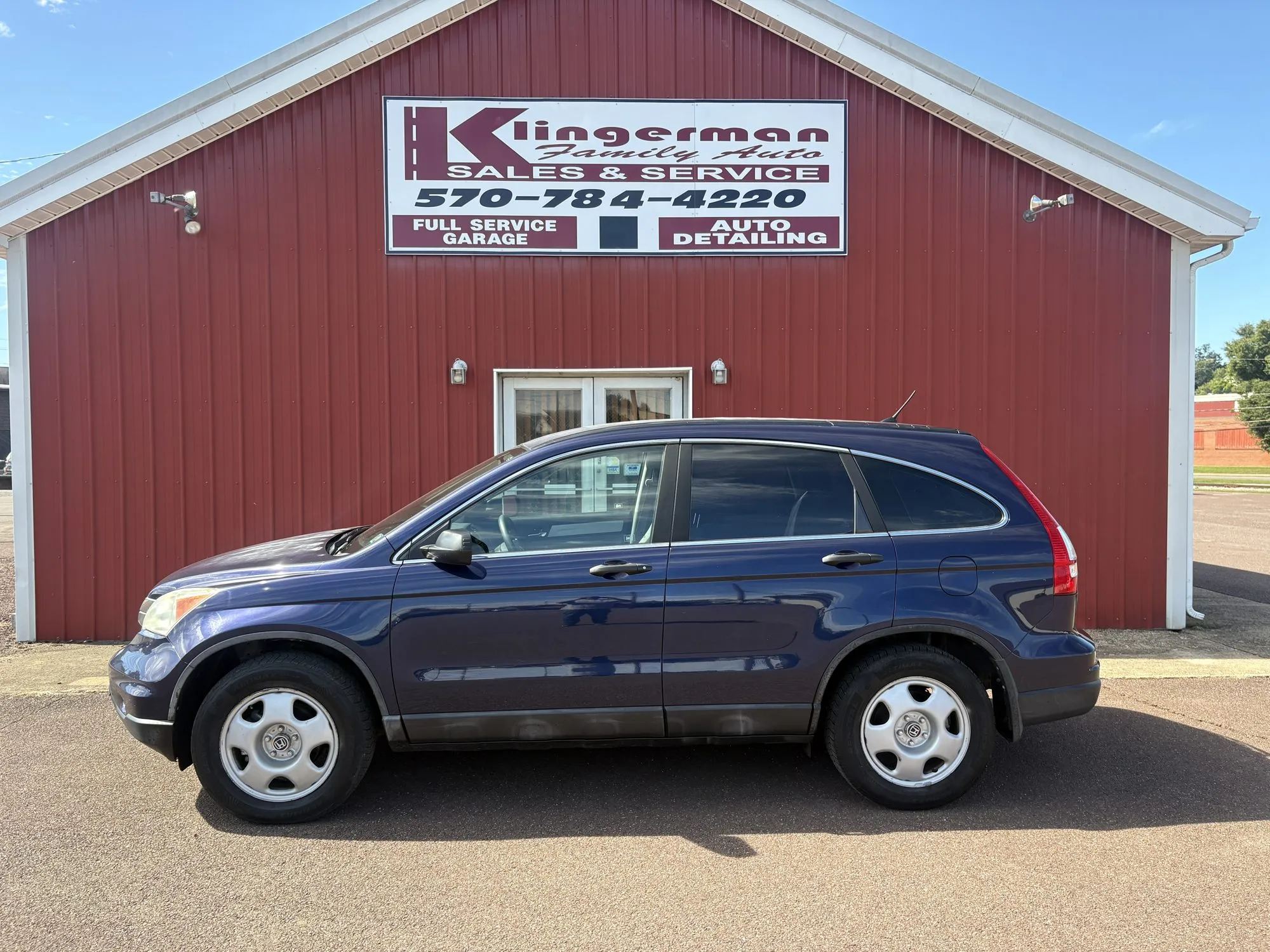 A dark blue 2011 Honda CR-V LX parked in front of the Klingerman Family Auto building