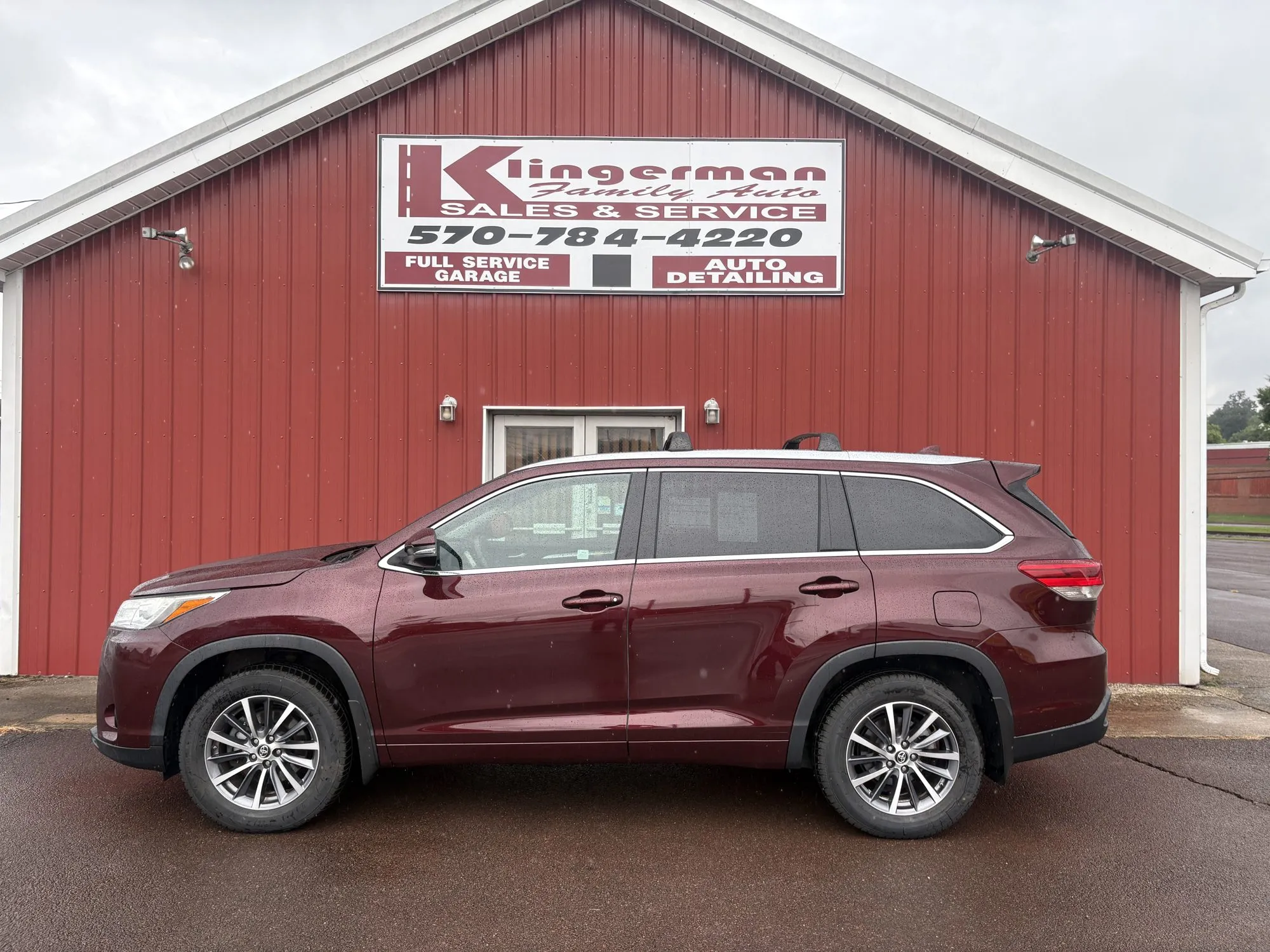 A burgundy 2018 Toyota Highlander parked in front of the Klingerman Family Auto building