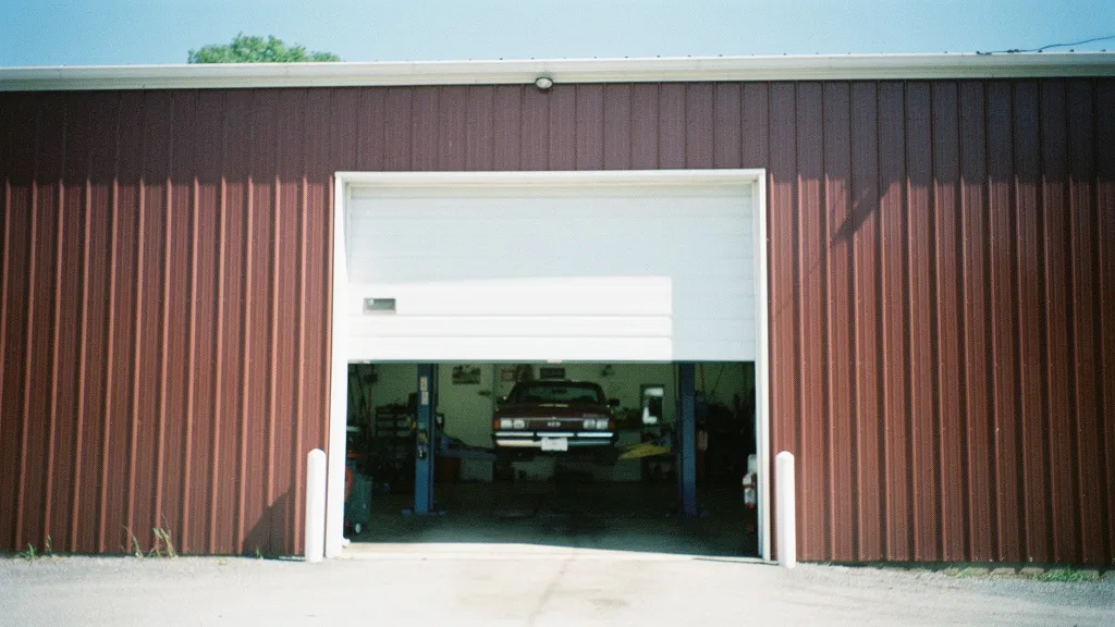 An open service bay door in the red siding of the shop